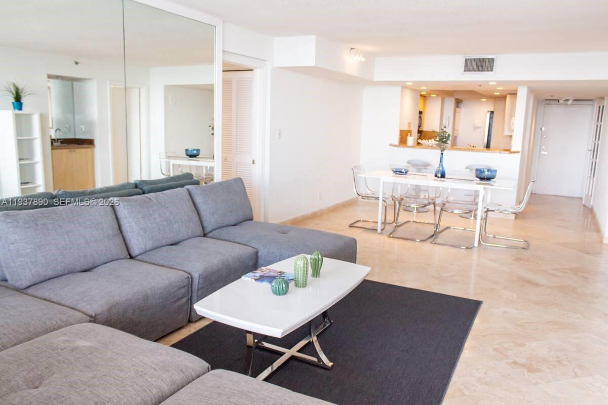 A living room features a gray sectional sofa, a white coffee table, and a dining area — 1717 N Bayshore Dr # 4141, Miami FL 33132, MIAMI, FL