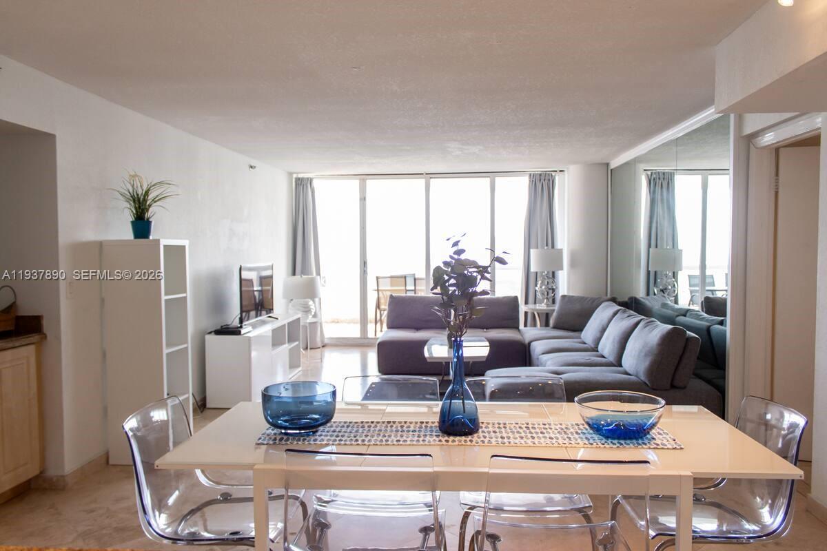 A dining area with a white table and clear chairs opens into a living room — 1717 N Bayshore Dr # 4141, Miami FL 33132, MIAMI, FL