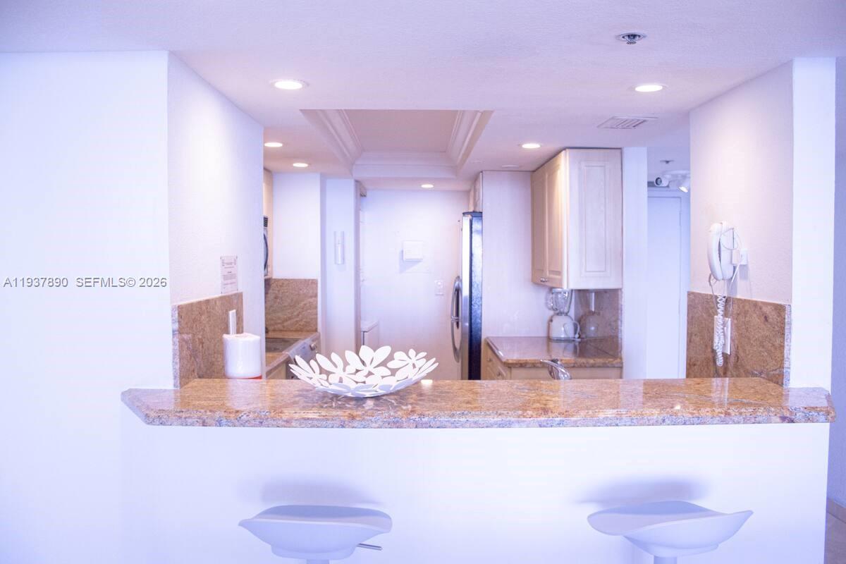 A kitchen features granite countertops, light-colored cabinetry, and a breakfast bar with two stools — 1717 N Bayshore Dr # 4141, Miami FL 33132, MIAMI, FL