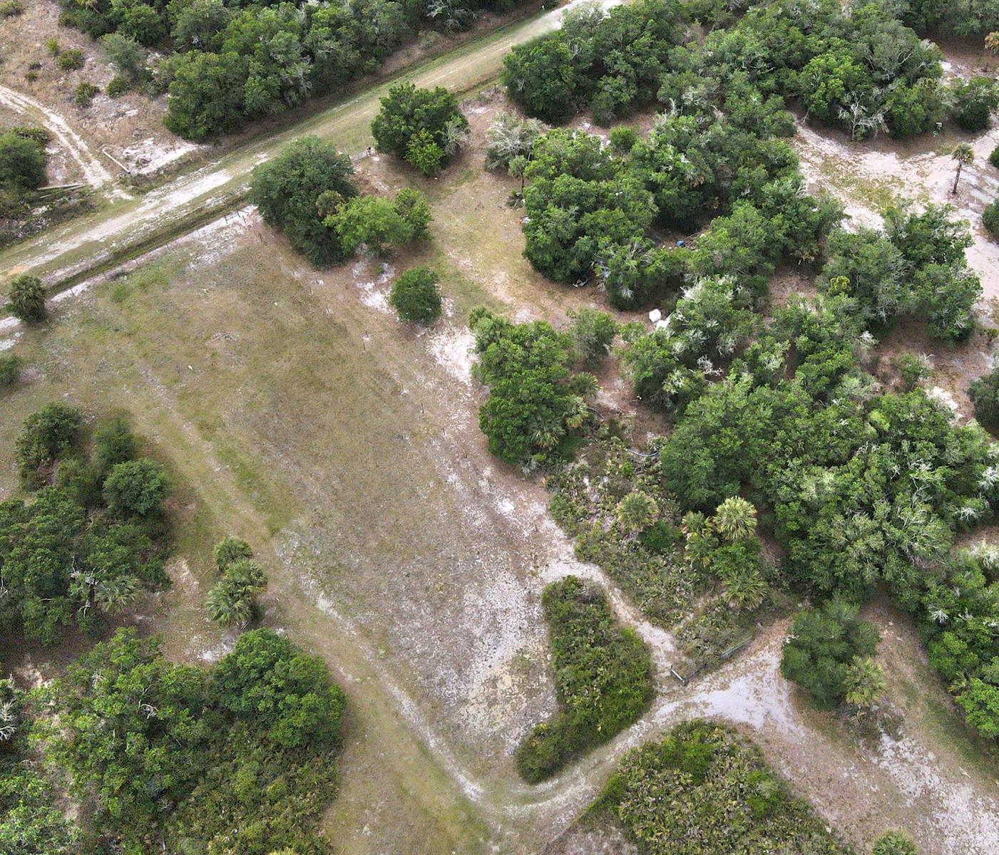 An aerial view shows a grassy, partially wooded lot with a dirt path and vegetation — 21877 NW 286th Street, Okeechobee FL 34972, OKEECHOBEE, FL