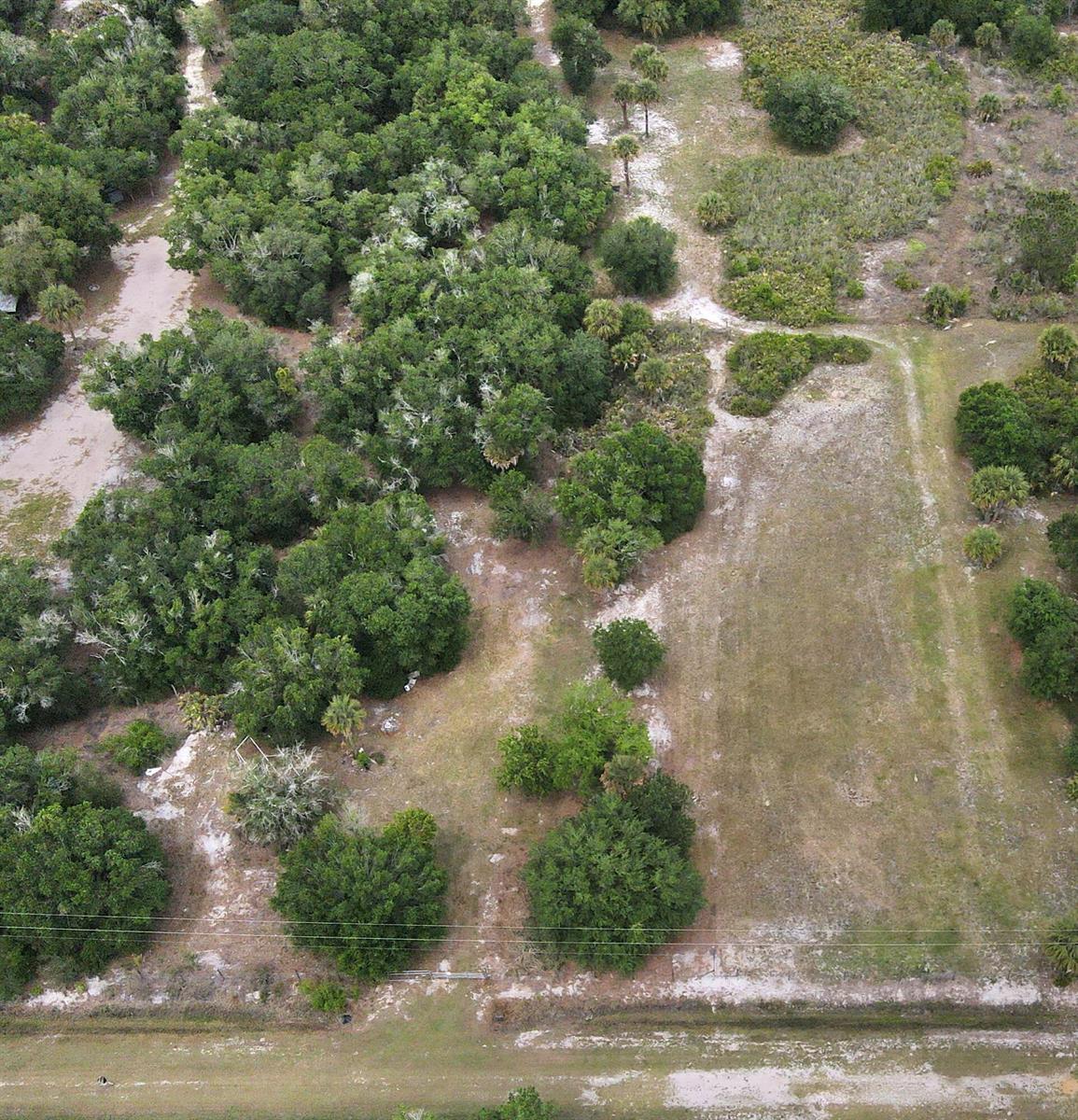 An aerial view shows a grassy lot bordered by dense trees and a dirt road — 21877 NW 286th Street, Okeechobee FL 34972, OKEECHOBEE, FL