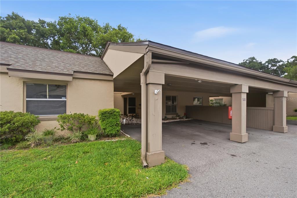 A beige single-story building features a covered carport with square support pillars and a driveway — 520 WINDMEADOWS STREET UNIT 520, ALTAMONTE SPRINGS, FL