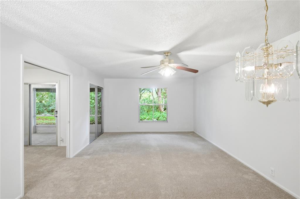 A bright living room features beige carpeting, a ceiling fan, and a crystal chandelier — 520 WINDMEADOWS STREET UNIT 520, ALTAMONTE SPRINGS, FL