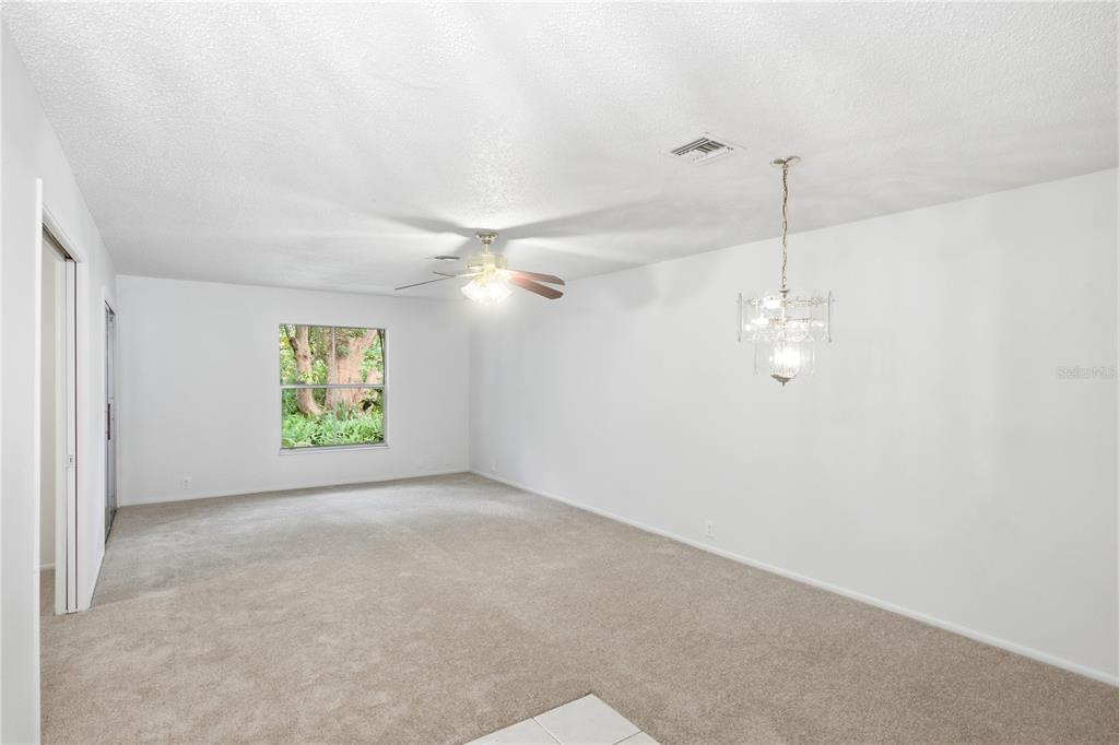 An empty room with beige carpet, white walls, a ceiling fan, and a crystal chandelier — 520 WINDMEADOWS STREET UNIT 520, ALTAMONTE SPRINGS, FL