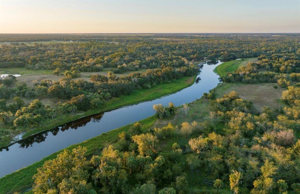 An aerial view of a winding river flowing through a forested landscape and open fields — 1061 HARRIS ROAD, ARCADIA, FL