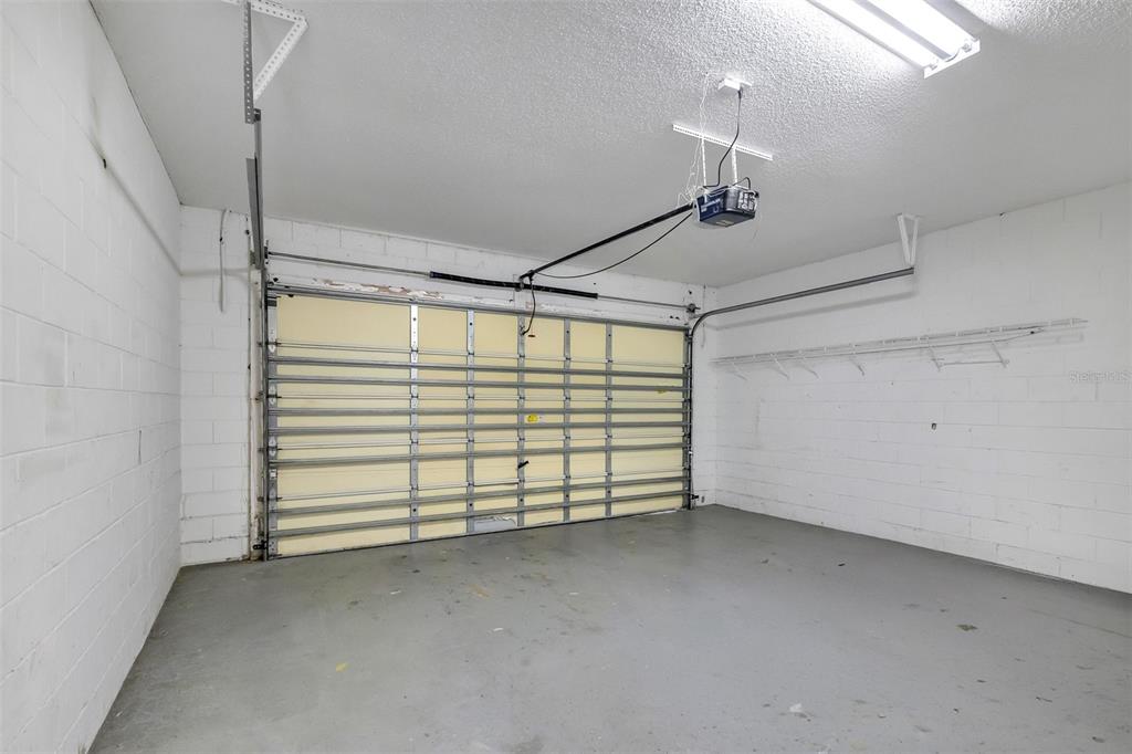 An empty garage with white concrete block walls, a gray floor, and a sectional door — 1720 BEAR BAY COVE, ORLANDO, FL
