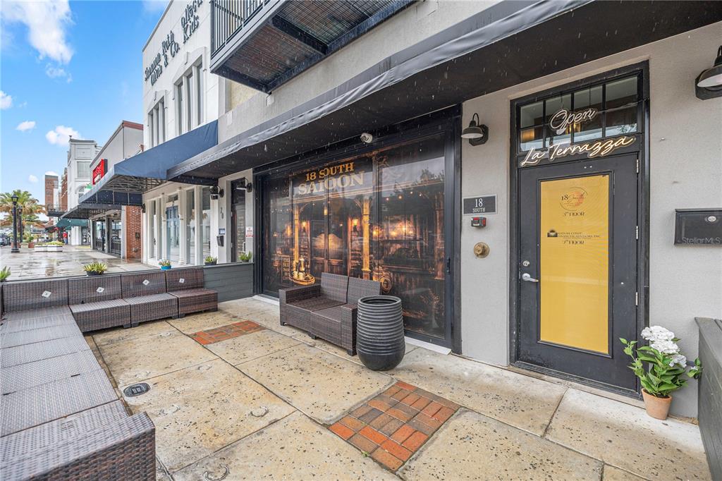 An outdoor patio area features wicker furniture, a large planter, and a storefront entrance — 18 S MAGNOLIA AVENUE, OCALA, FL