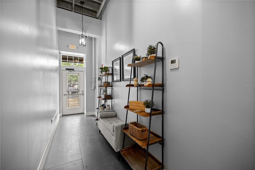 A narrow hallway features gray tile flooring, a light gray bench, and two metal shelving units — 18 S MAGNOLIA AVENUE, OCALA, FL