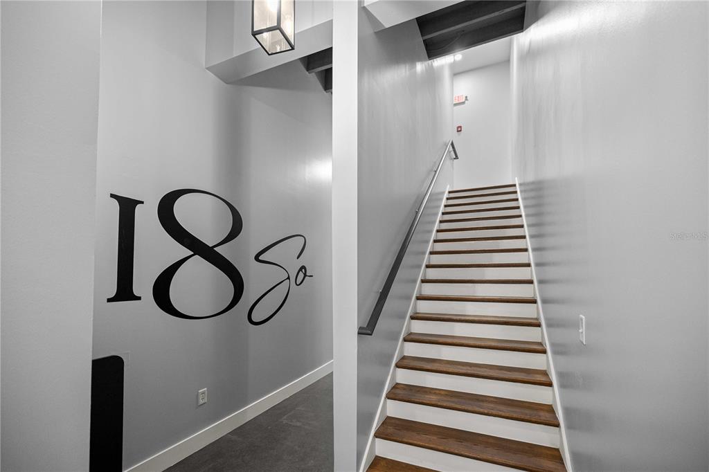 A staircase with wooden treads and white risers leads upward between two gray walls — 18 S MAGNOLIA AVENUE, OCALA, FL