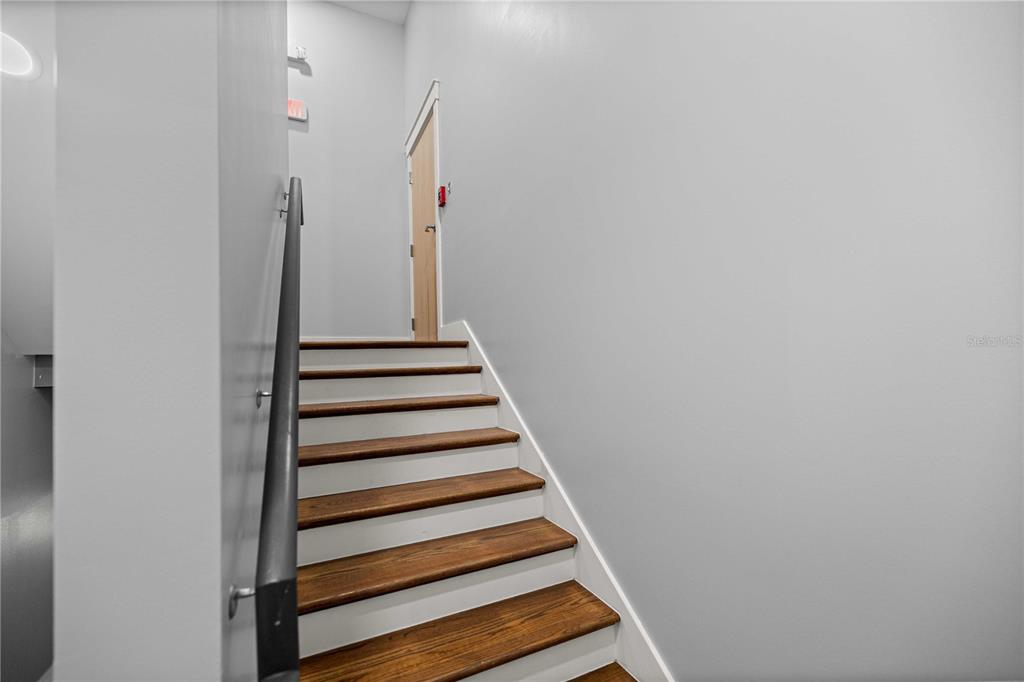 A staircase with wooden treads and white risers leads to a closed door — 18 S MAGNOLIA AVENUE, OCALA, FL