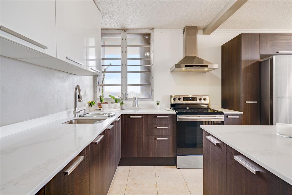 A kitchen features dark wood lower cabinets, white upper cabinets, white countertops, and stainless appliances — 1704 SAN PATRICIO AVENUE UNIT 1704, GUAYNABO, PR