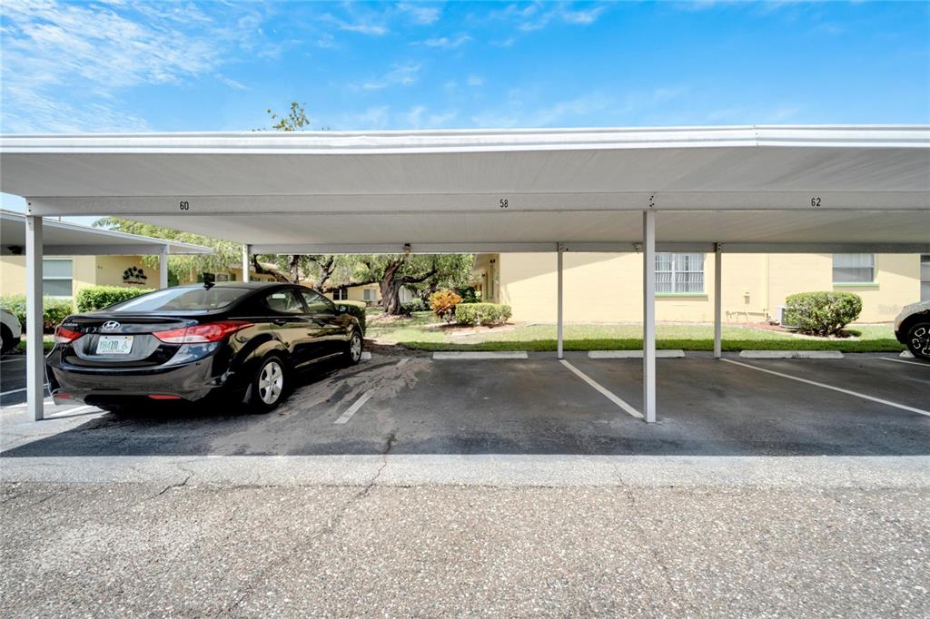 A covered parking area features numbered spaces and a black sedan parked in spot 60 — 401 DORCHESTER PLACE UNIT 58, SUN CITY CENTER, FL