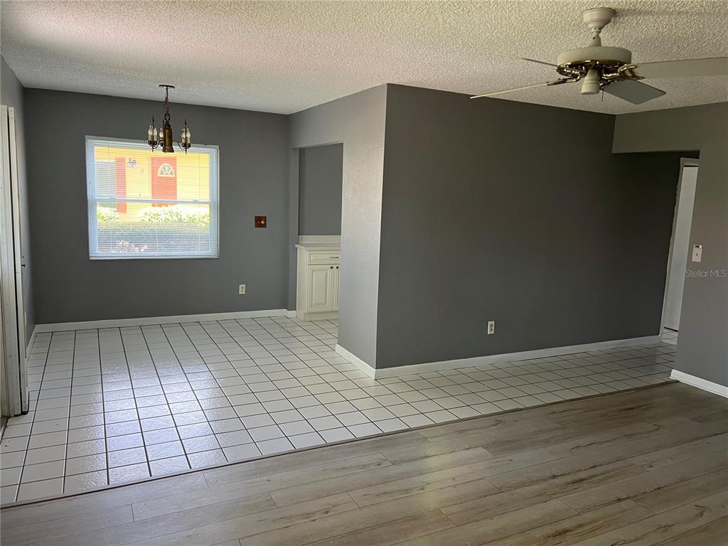 A dining area with white tile flooring transitions into a living space with wood-look flooring — 401 DORCHESTER PLACE UNIT 58, SUN CITY CENTER, FL