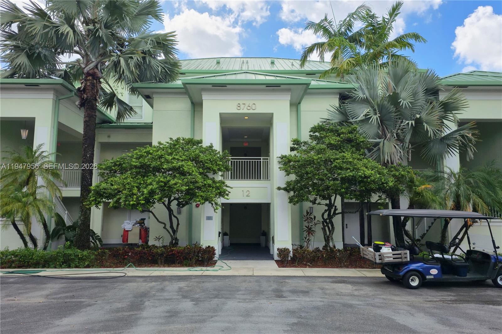 The exterior of a multi-story building features a green metal roof and palm trees — 5300 NW 87Th Ave # 1212, Doral FL 33178, DORAL, FL