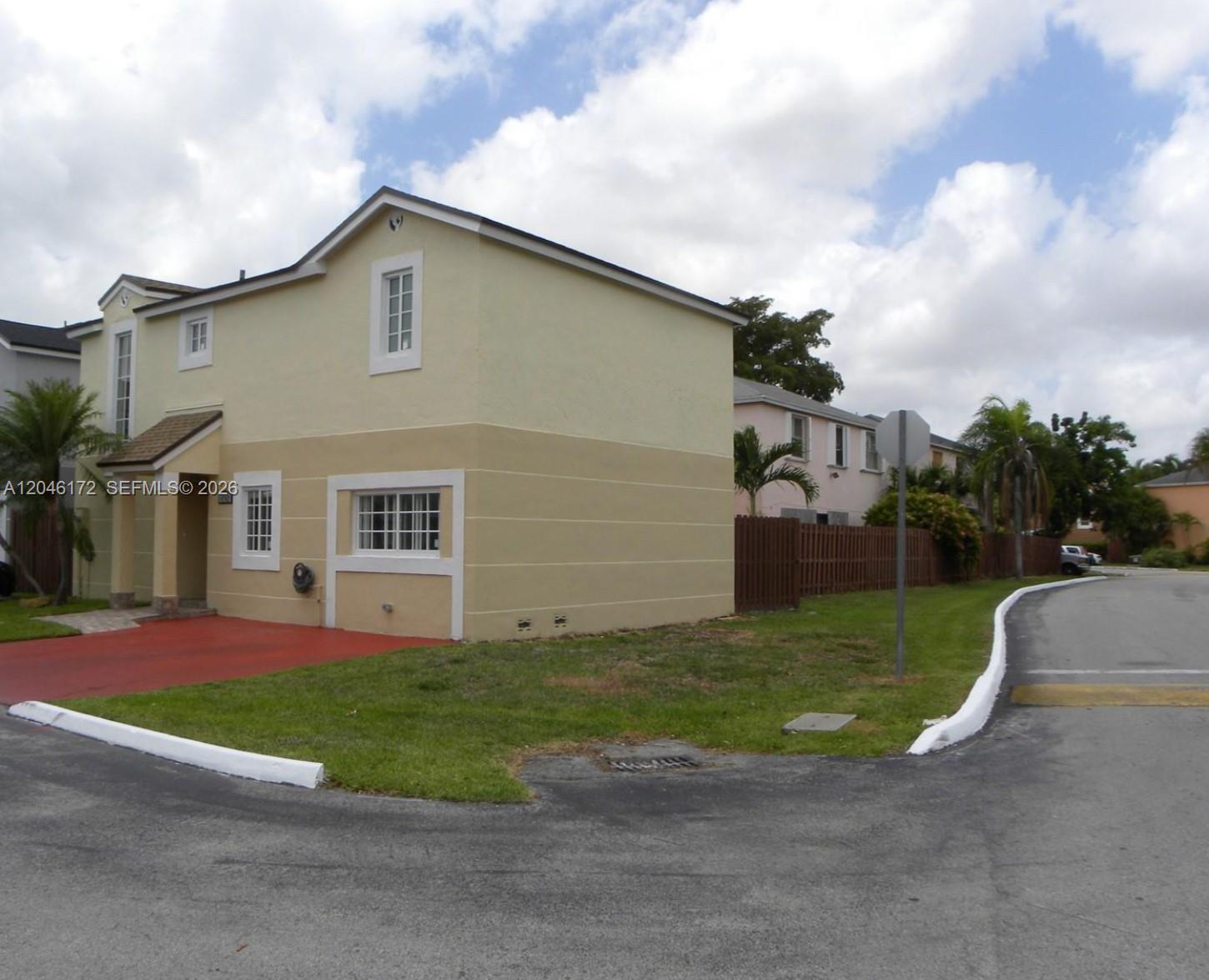 A two-story yellow stucco house with a red driveway sits on a corner lot — 14742 SW 92nd St Rd, Miami FL 33196, MIAMI, FL