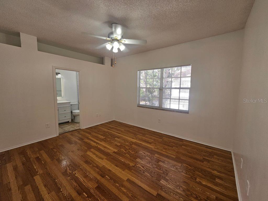 A bedroom with wood-look flooring, a ceiling fan, and an attached bathroom — 601 BAINBRIDGE DRIVE, BRANDON, FL