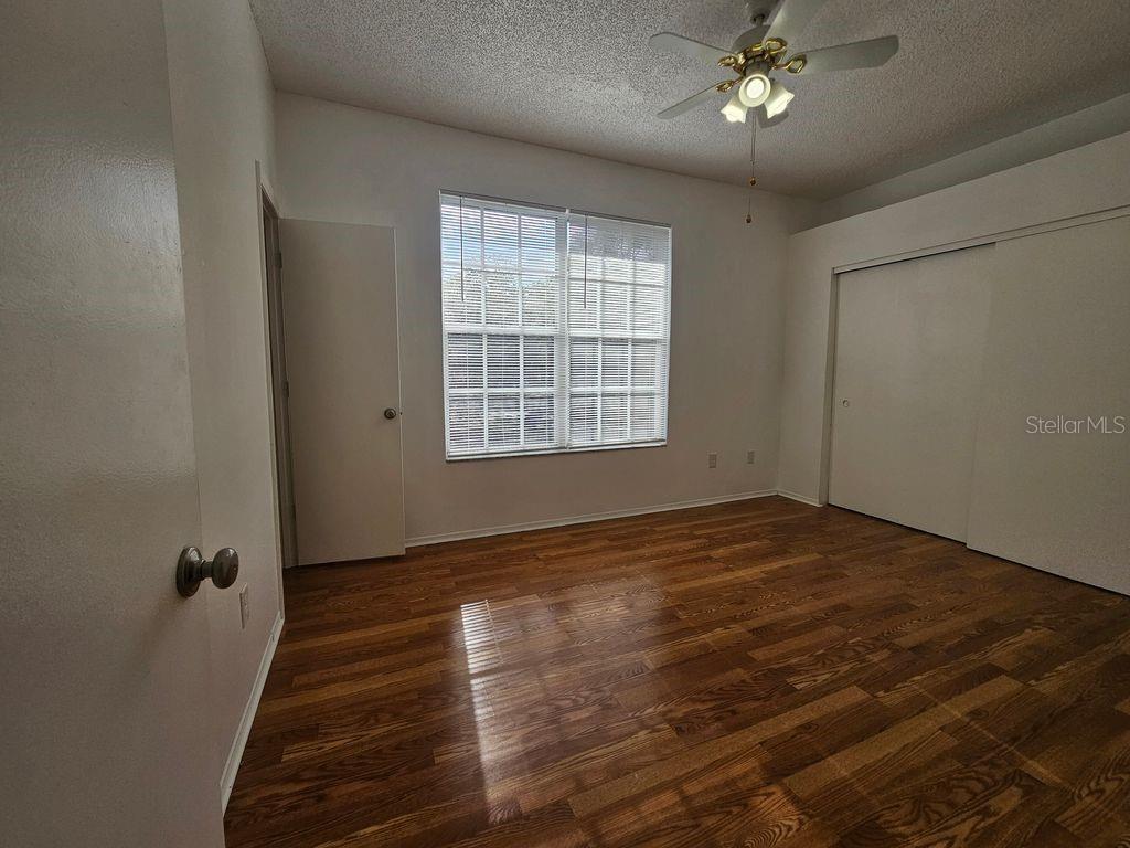 An empty bedroom features wood-look flooring, a ceiling fan, a window with blinds, and closets — 601 BAINBRIDGE DRIVE, BRANDON, FL