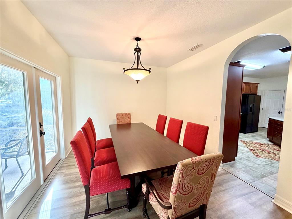 A dining room features a dark wood table, red chairs, and a pendant light fixture — 1043 SE COUNTY ROAD 21B, MELROSE, FL