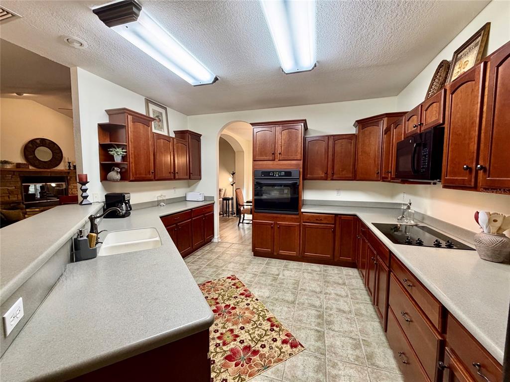 A kitchen features dark wood cabinets, gray countertops, a built-in oven, and tile flooring — 1043 SE COUNTY ROAD 21B, MELROSE, FL