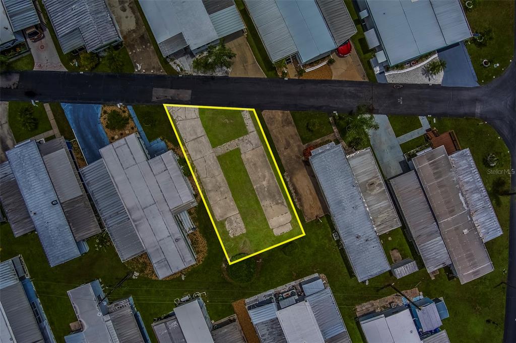 An aerial view shows a vacant lot with a concrete driveway pad between two mobile homes — 16940 US HIGHWAY 19 N UNIT 244, CLEARWATER, FL