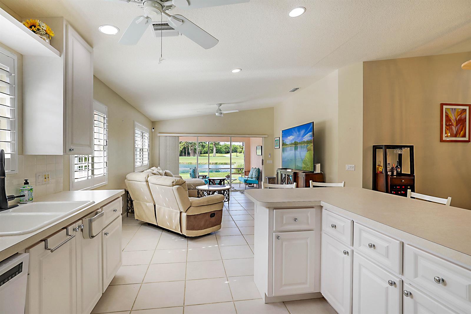 A white kitchen overlooks a living area with a view of a lake and golf course — 1134 SW Balmoral Trace, Stuart FL 34997, STUART, FL