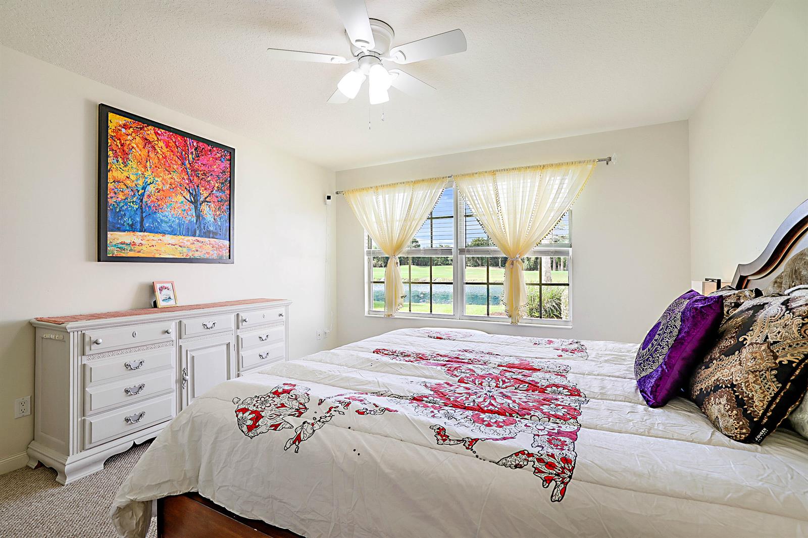 A bedroom features a white dresser, a bed with patterned bedding, and a window overlooking water — 1134 SW Balmoral Trace, Stuart FL 34997, STUART, FL