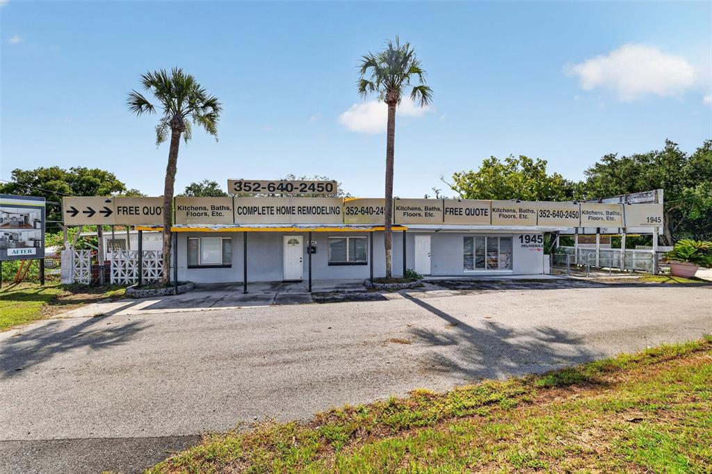 A single-story commercial building with a gray facade and multiple signs advertising home remodeling services — 1945 S US HIGHWAY 441, LADY LAKE, FL
