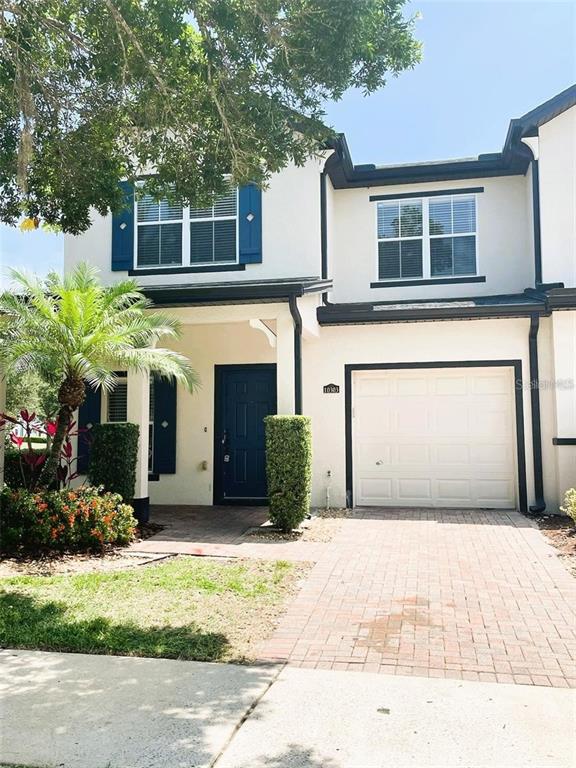 A two-story townhouse with a white stucco facade, blue shutters, and a single-car garage — 10303 PARK COMMONS DRIVE, ORLANDO, FL