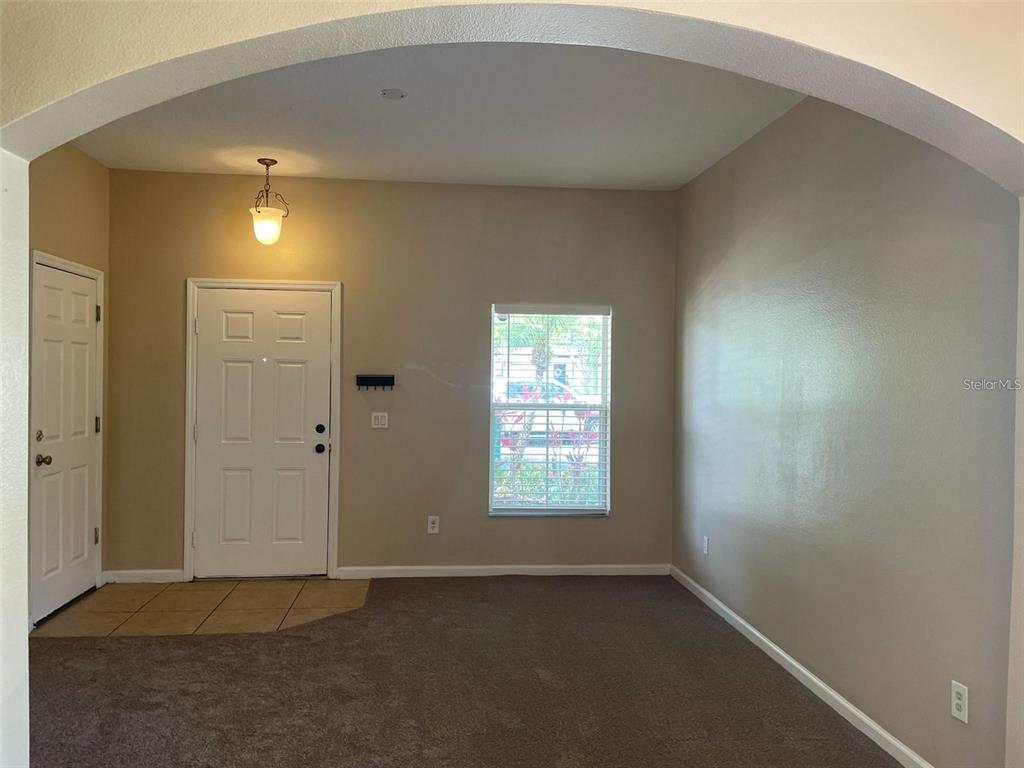 An entryway features a white door, a window, beige walls, and brown carpeted flooring — 10303 PARK COMMONS DRIVE, ORLANDO, FL