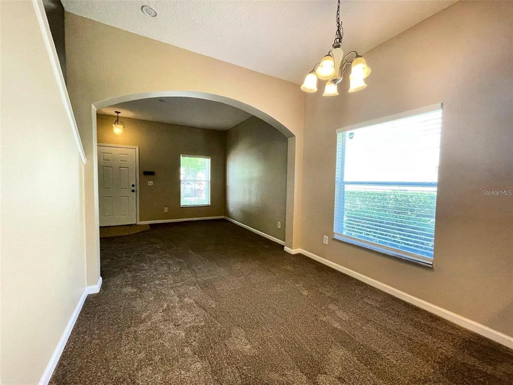 A carpeted dining area features a chandelier, an arched entryway, and a large window — 10303 PARK COMMONS DRIVE, ORLANDO, FL