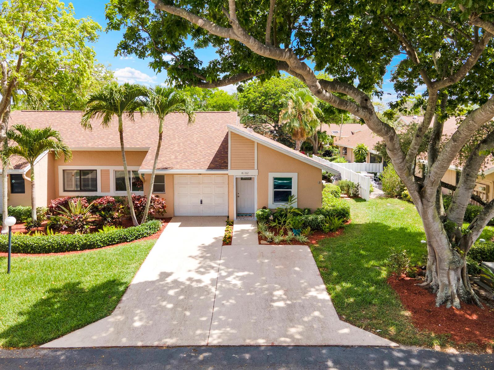 A single-story house with a tan exterior, a white garage door, and a concrete driveway — 8182 Springtree Road, Boca Raton FL 33496, BOCA RATON, FL