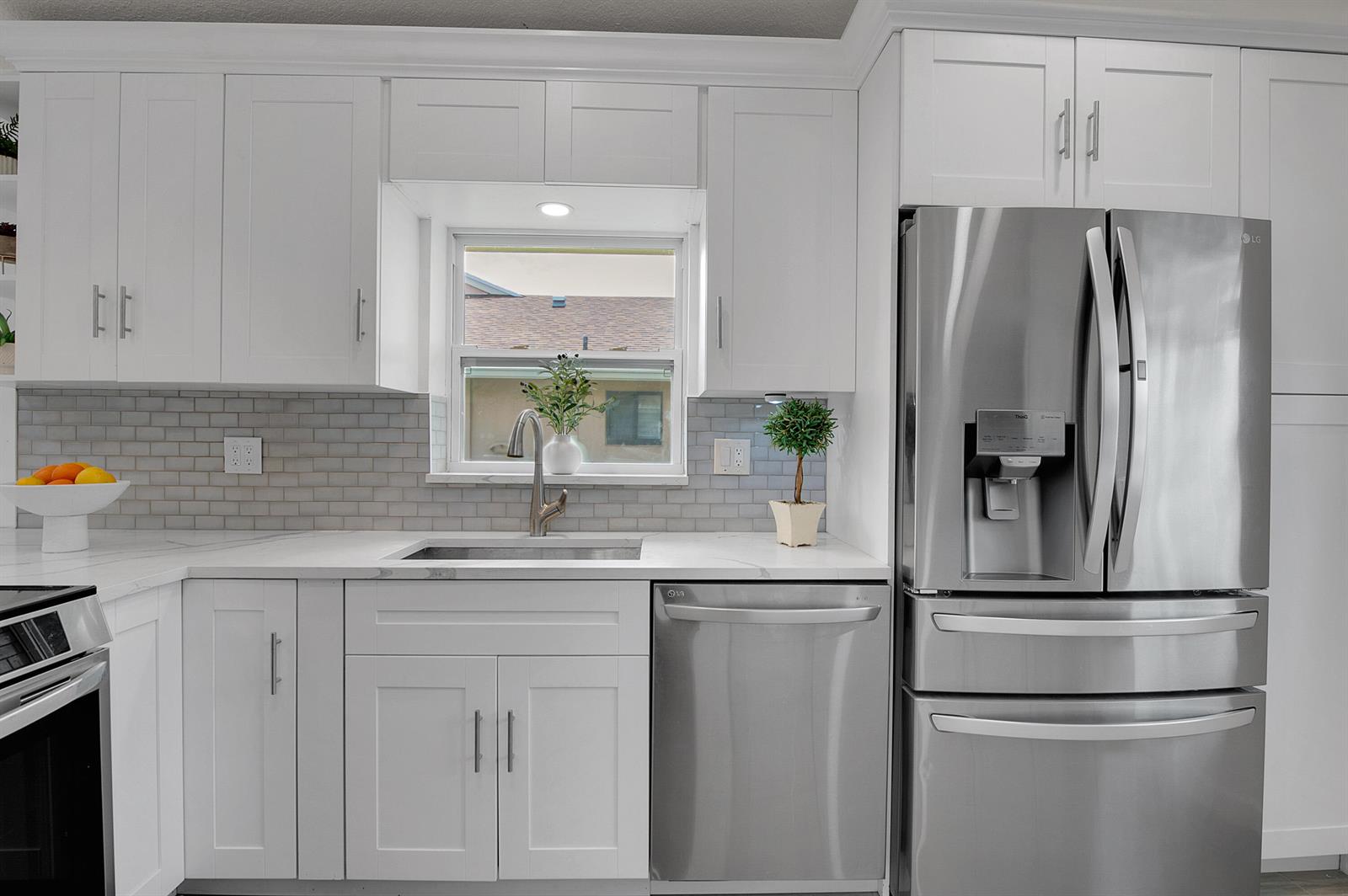 A modern kitchen features white cabinets, stainless steel appliances, a subway tile backsplash, and countertops — 8182 Springtree Road, Boca Raton FL 33496, BOCA RATON, FL
