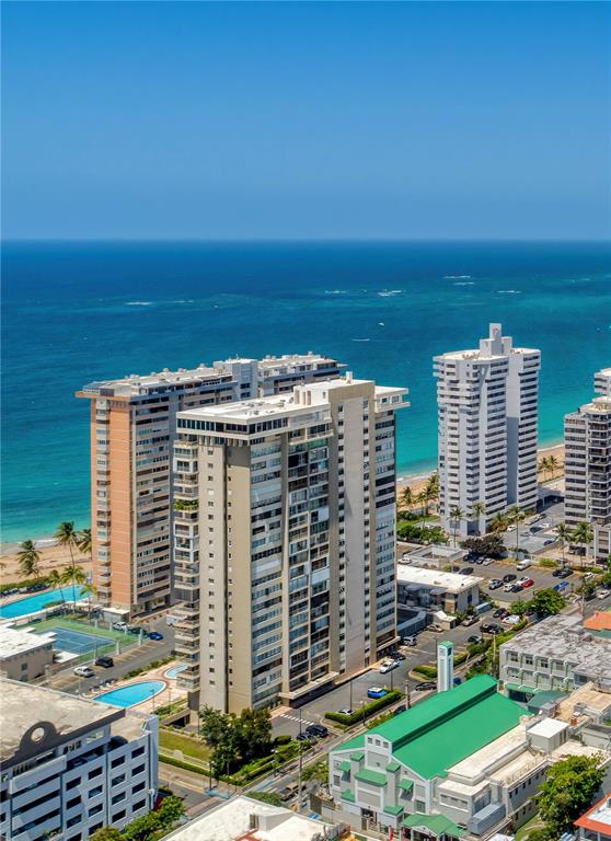 An aerial view shows high-rise apartment buildings situated along a sandy beach and ocean — 1477 ASHFORD AVENUE UNIT 2206, SAN JUAN, PR