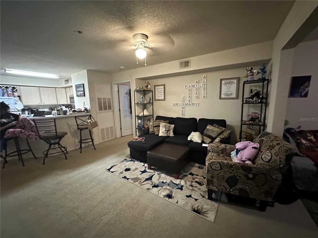 A living room with a sectional sofa, patterned armchair, and an open kitchen with bar seating — 822 CAMARGO WAY UNIT 105, ALTAMONTE SPRINGS, FL