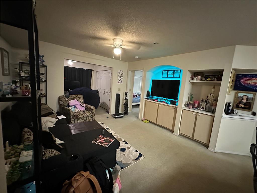 A living room features a black sectional sofa, a patterned armchair, and a built-in media center — 822 CAMARGO WAY UNIT 105, ALTAMONTE SPRINGS, FL