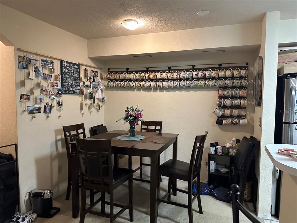 A dining area features a dark wood table, chairs, and extensive wall-mounted mug storage racks — 822 CAMARGO WAY UNIT 105, ALTAMONTE SPRINGS, FL