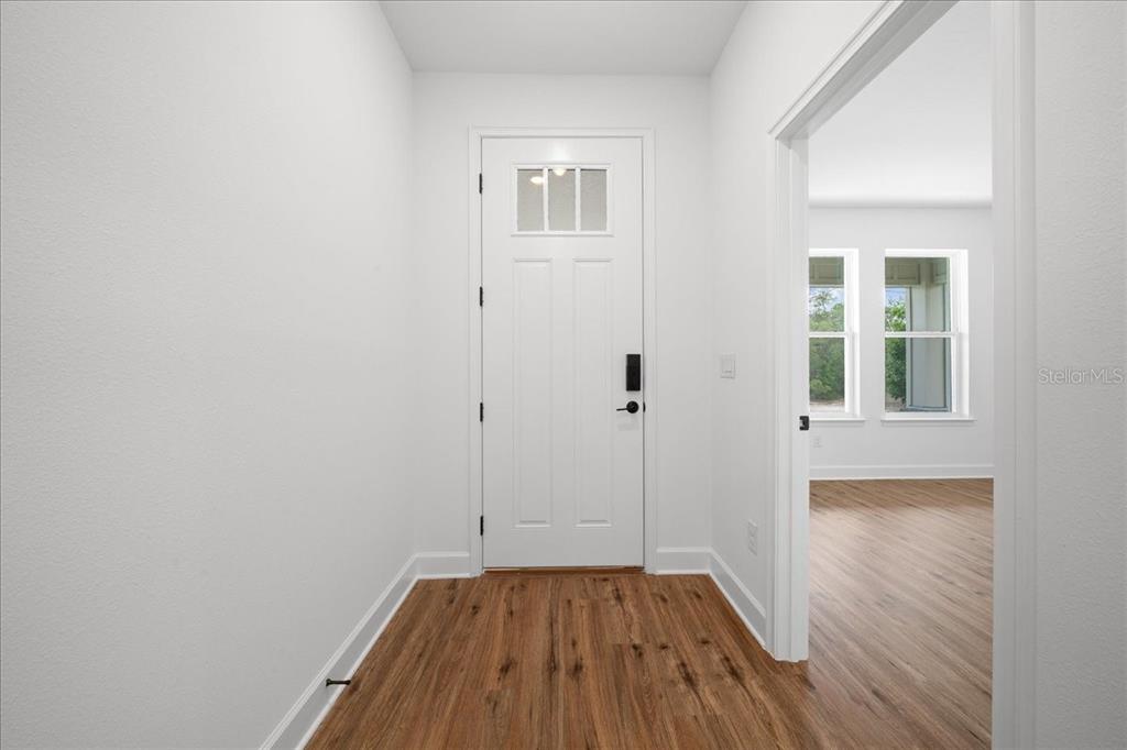 An entryway with white walls, wood-look flooring, and a white front door — 15095 SNOWY OWL AVENUE, WEEKI WACHEE, FL