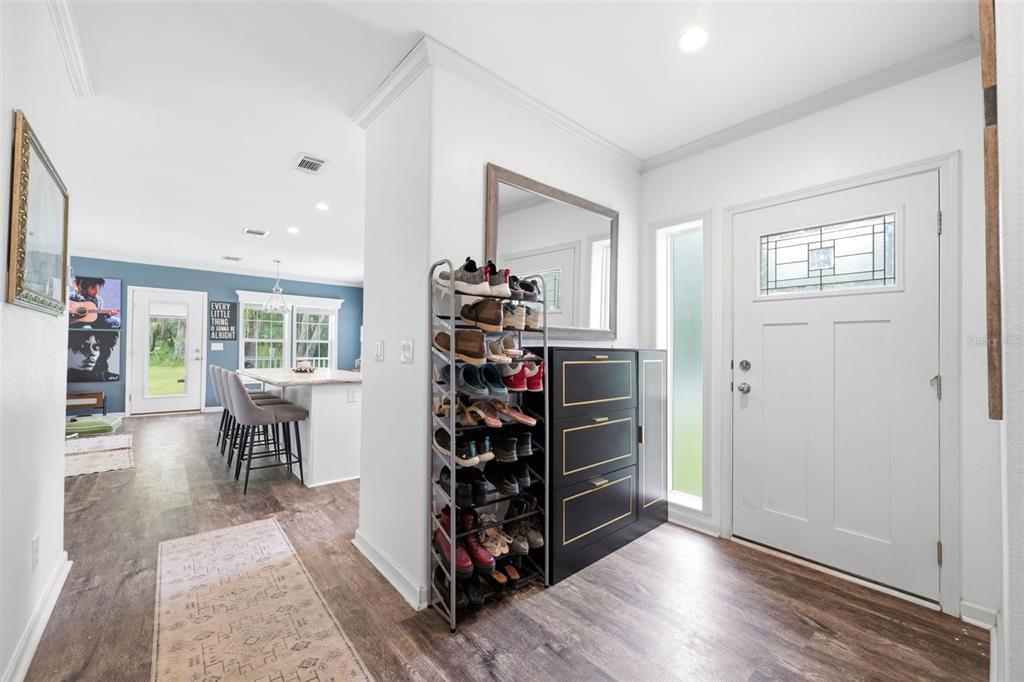 An entryway features wood-look flooring, a shoe rack, a storage cabinet, and a white front door — 16184 PAXFORD LANE, BROOKSVILLE, FL