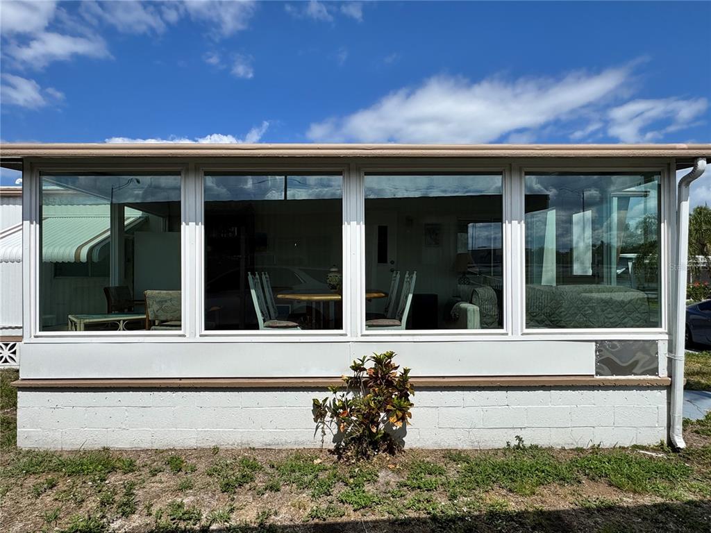 The exterior view shows a sunroom with large windows above a white concrete base — 420 49TH STREET E UNIT 20, PALMETTO, FL
