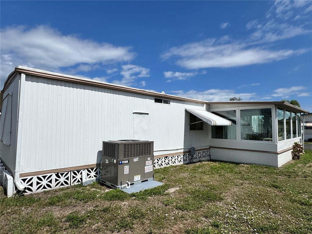 The exterior of a manufactured home features white siding, a York HVAC unit, and a sunroom — 420 49TH STREET E UNIT 20, PALMETTO, FL