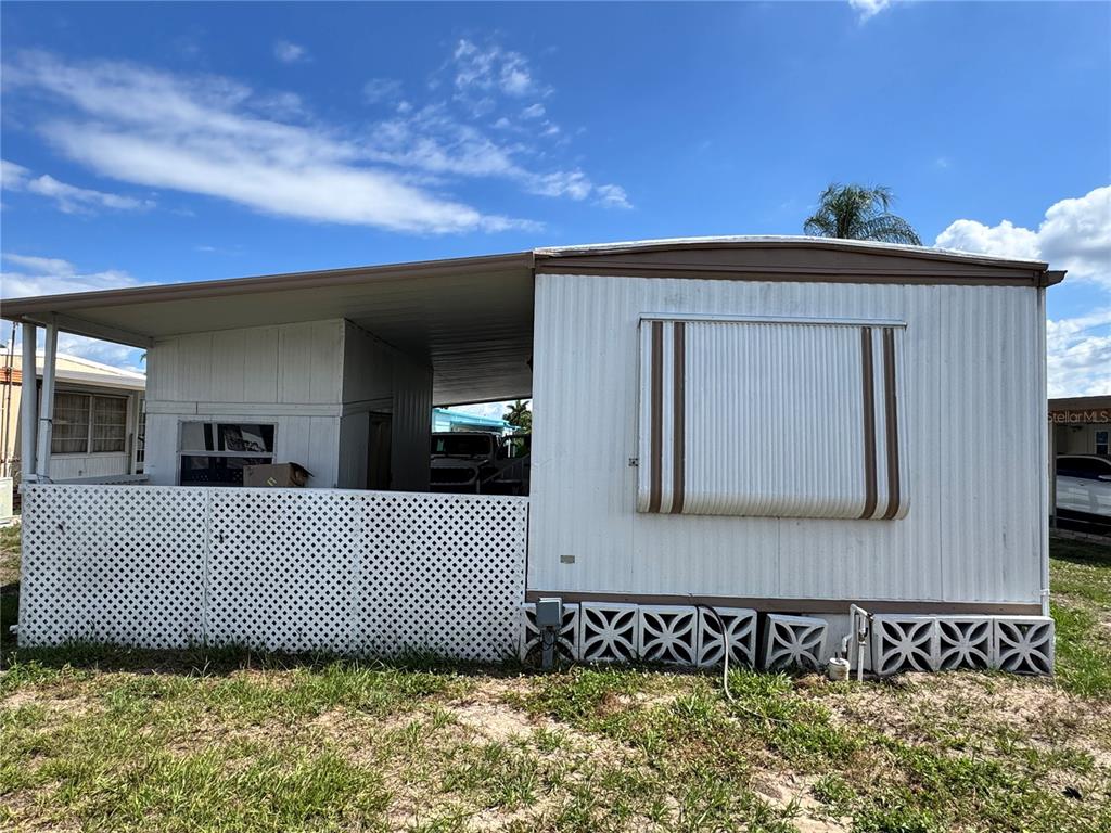 A mobile home exterior features a white lattice fence, a carport, and a window awning — 420 49TH STREET E UNIT 20, PALMETTO, FL