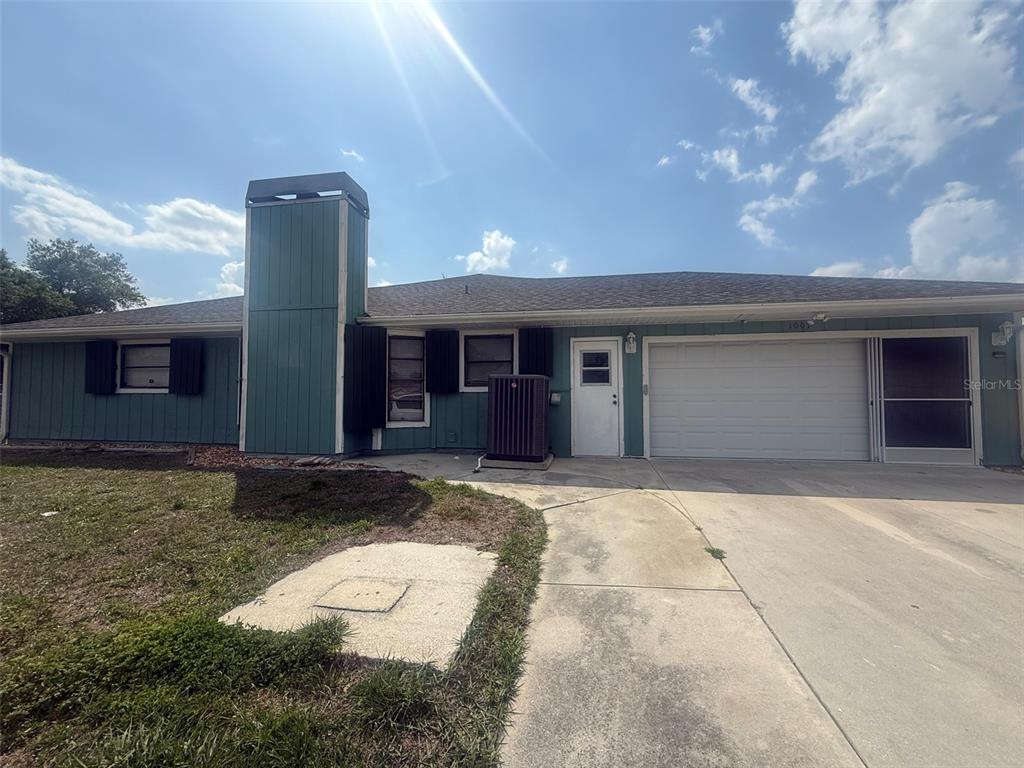 A single-story house with teal siding, a chimney, a garage, and a concrete driveway — 1001 S WAPELLO STREET, NORTH PORT, FL