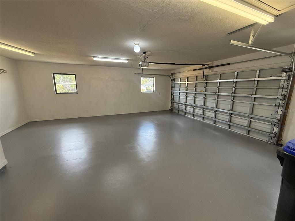 An empty garage with a gray painted floor, white walls, and a sectional door — 1001 S WAPELLO STREET, NORTH PORT, FL