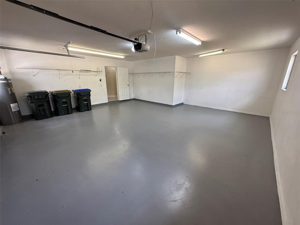 A spacious, empty garage features a gray painted floor, white walls, and overhead lighting — 1001 S WAPELLO STREET, NORTH PORT, FL
