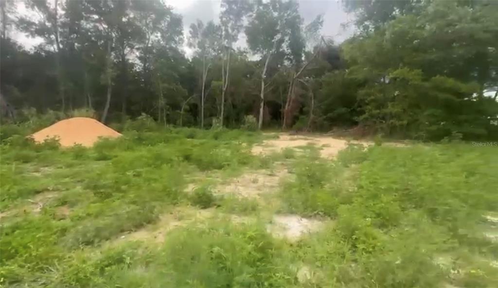 A vacant, grassy lot with a pile of dirt near a line of trees — 5311 NW 7TH STREET, OCALA, FL