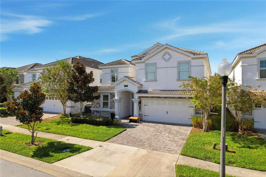 A two-story suburban house with a white stucco exterior, stone accents, and a paved driveway — 1584 SANDBAGGER DRIVE, DAVENPORT, FL