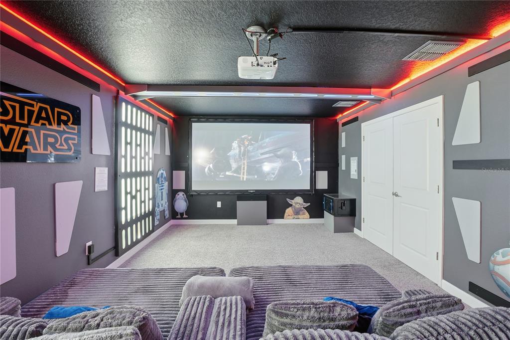 A Star Wars-themed home theater features a projector screen, tiered seating, and ambient red lighting — 1584 SANDBAGGER DRIVE, DAVENPORT, FL