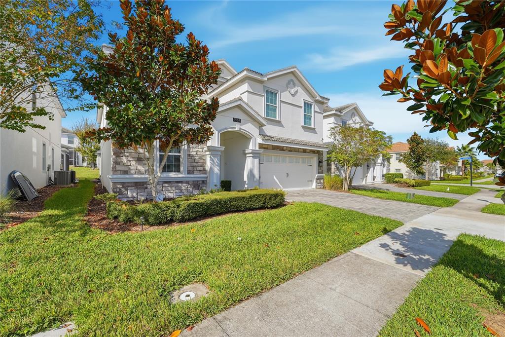A two-story suburban house with a stone facade, white stucco, and a paved driveway — 1584 SANDBAGGER DRIVE, DAVENPORT, FL