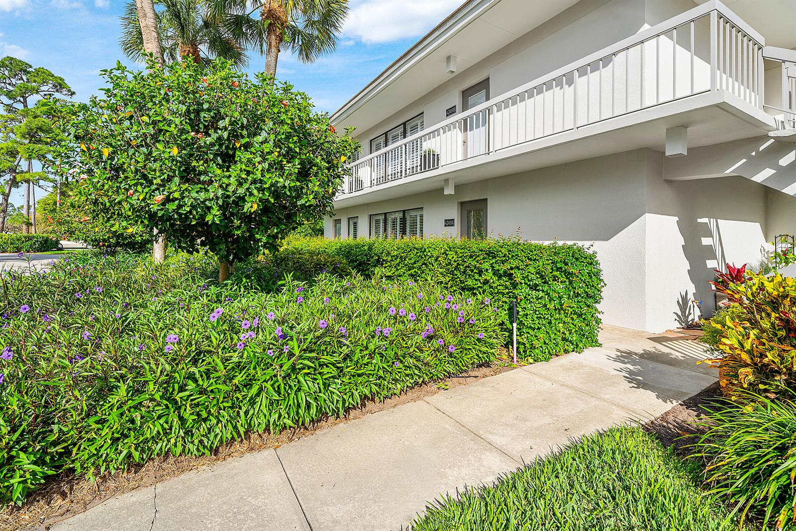 A two-story building exterior features a white balcony, a concrete walkway, and lush landscaping — 4249 N Quail Ridge Dr Drive # A, Boynton Beach FL 33436, BOYNTON BEACH, FL