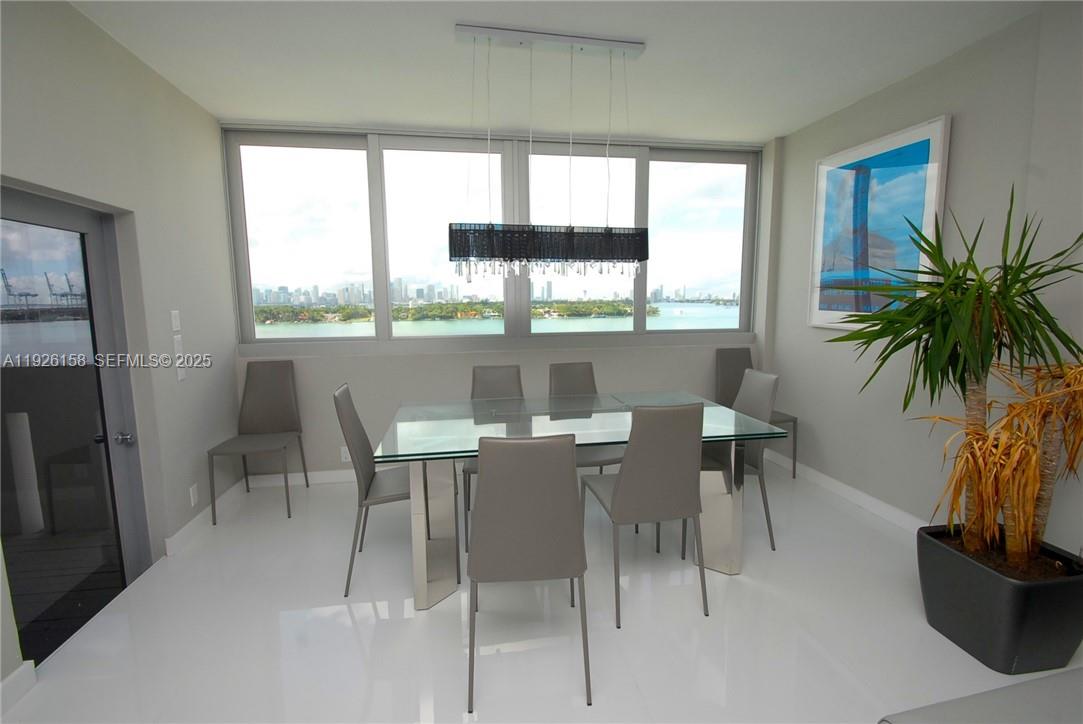 A dining room features a glass table, gray chairs, and a large window with water views — 800 West Ave, Miami Beach FL 33139, MIAMI BEACH, FL